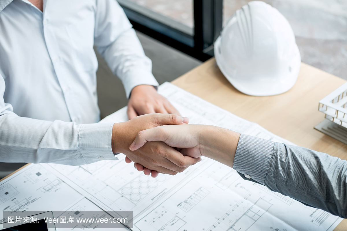 合作伙伴握手,建筑工程或建筑師討論藍(lán)圖和建筑模型,同時檢查草圖信息,為建筑項目的合作伙伴舉行會議